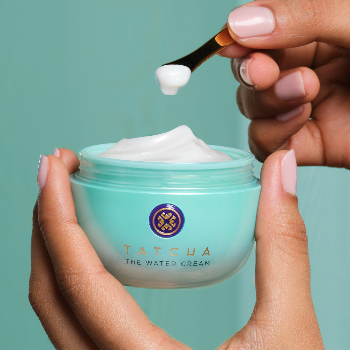 Hand scooping out Water Cream Moisturizer with a gold spoon