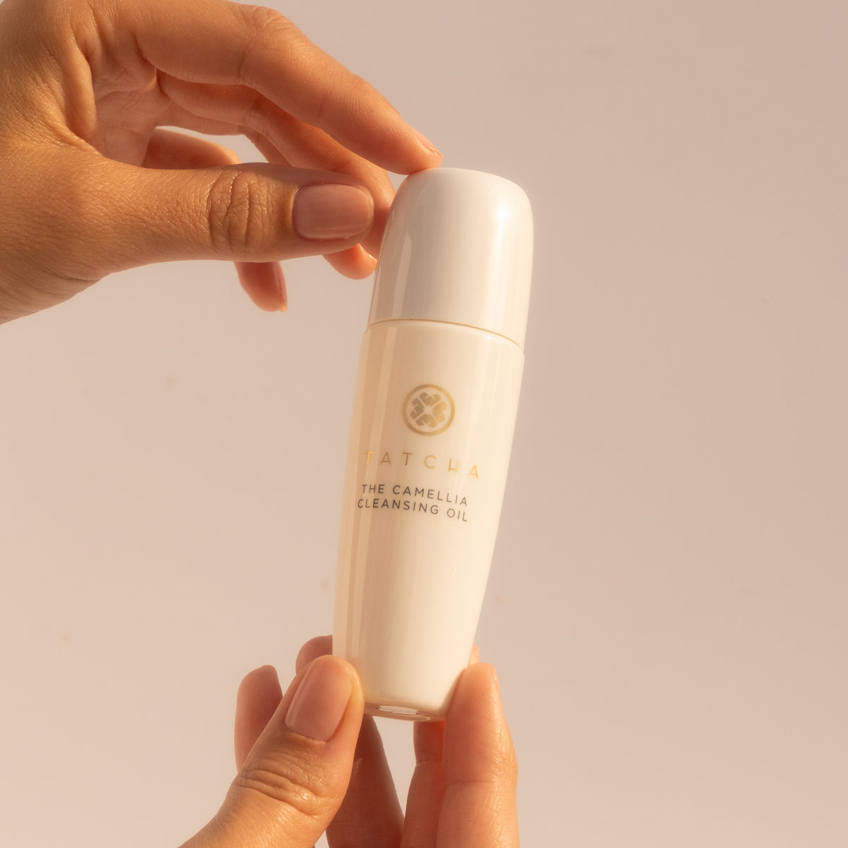 Hands holding a mini Camellia Cleansing Oil
