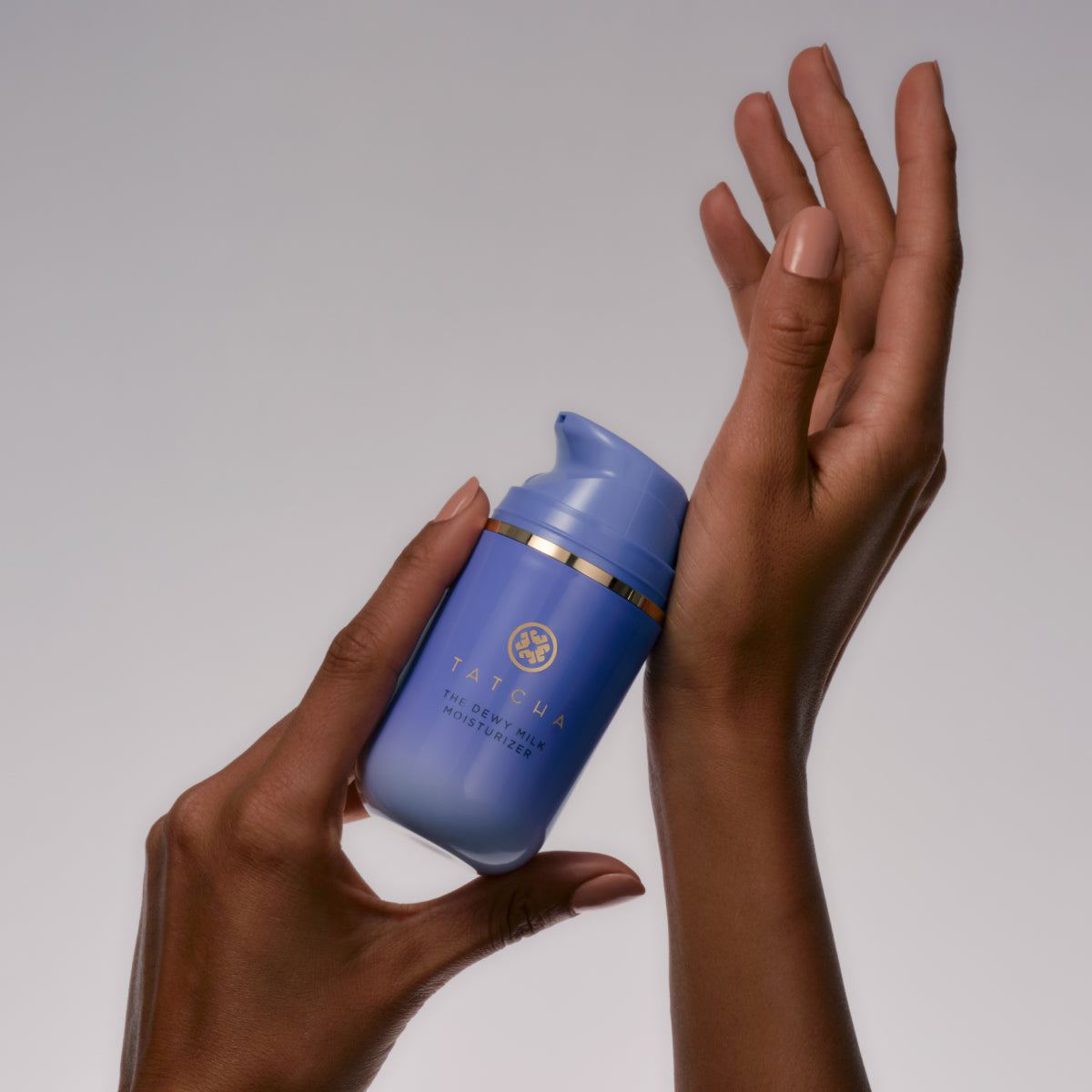 Hands holding the Tatcha Dewy Milk Moisturizer