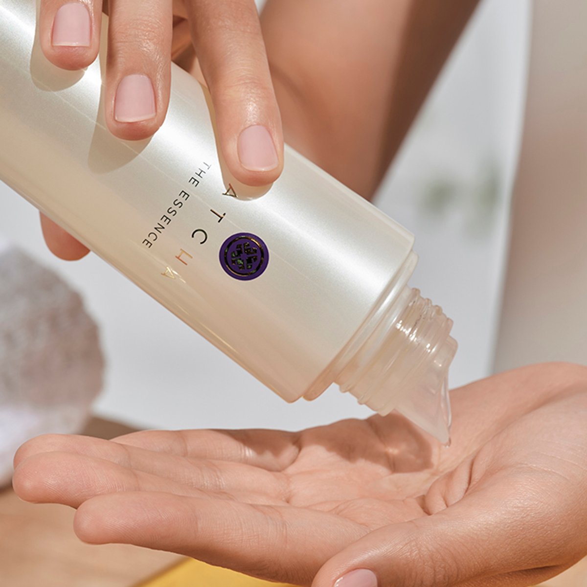 Shot of model pouring The Essence onto hands.