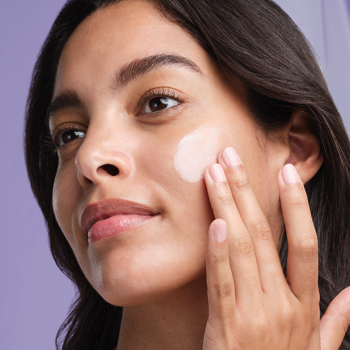 Shot of model applying The Silk Serum onto cheek.